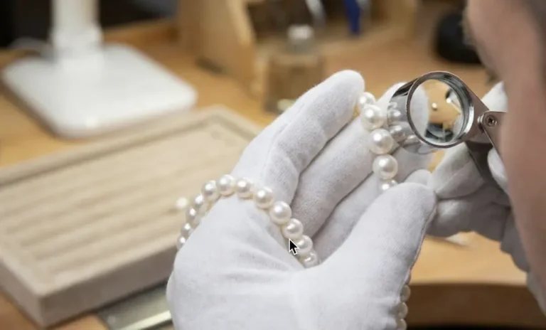 The Professional's Guide to Identifying Real Freshwater Pearls: Beyond the Tooth Test 8 Professional jeweler identifying real freshwater pearls using a 10x loupe to inspect luster and surface quality.